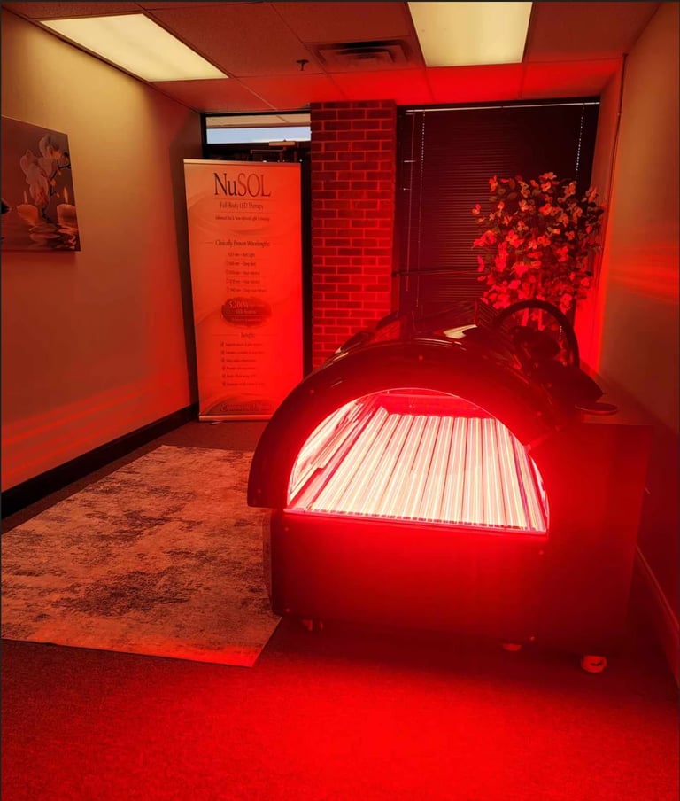 Red-lit tanning bed room with NuSOL branding sign, brick wall, and glowing tanning booth illuminated by red neon lighting